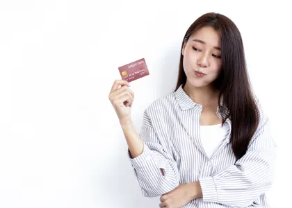 A woman holding a credit card, holding back a smile after finally getting one.