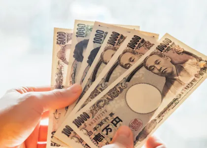 Hands holding out 37,000 Japanese yen to pay their taxes.