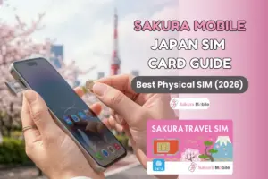 Hand inserting a physical SIM card from Sakura Mobile into a phone with cherry blossoms near Tokyo tower in the background.