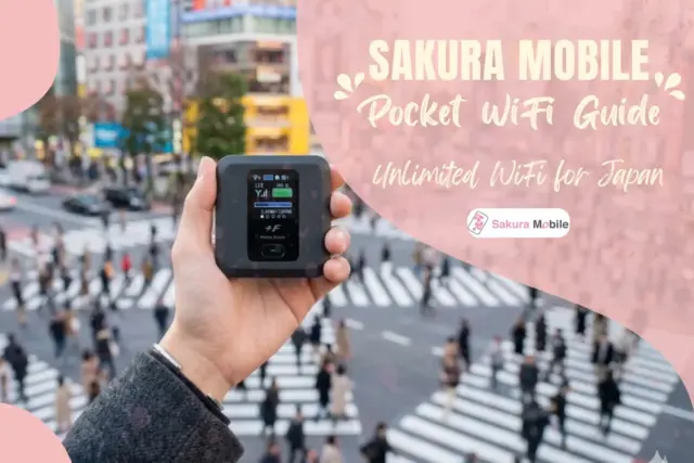 A hand holding a Sakura Mobile device in fornt of a busy Shibuya Scramble.