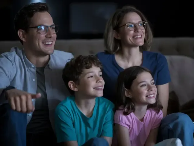 Family watching TV together on couch in cozy living room.
