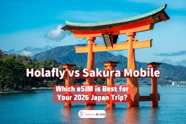 Itsukushima Shrine floating torii gate in Miyajima, Japan, standing in the water with mountains in the background under a clear, blue sky.
