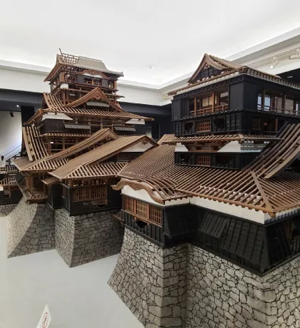 Kumamoto Castle’s wooden architectural, multi-tiered roofs, black walls, and steep stone foundation model inside museum
