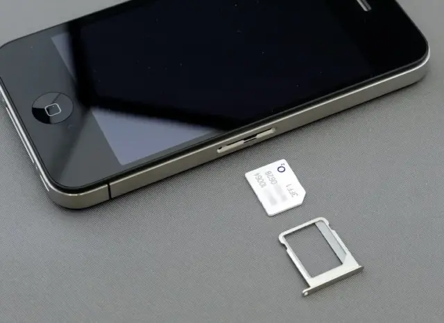 Close-up of a SIM card laying next to a smartphone, demonstrating the setup process for travelers using a physical SIM in Japan.