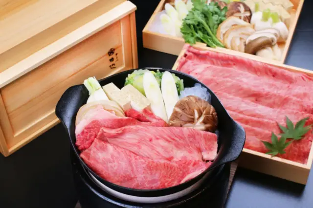 Japanese beef hot pot (gyunabe) featuring sliced raw beef, tofu, shiitake mushrooms, and green onions