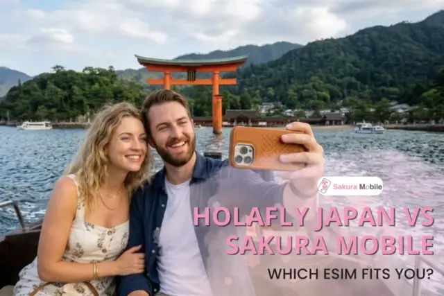 A couple taking a selfie on a boat with the famous torii gate and mountains of Miyajima in the background.