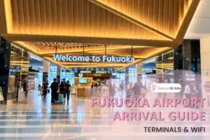 Travelers walk through the arrival hall at Fukuoka Airport under a large "Welcome to Fukuoka" sign.