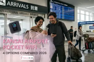 Couple arrives at Kansai International Airport (KIX), smiling and looking at phones, with luggage.