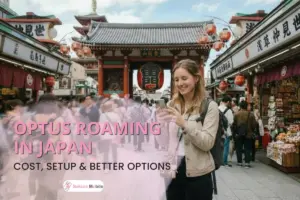 A smiling tourist uses her phone in front of the large Kaminarimon gate at Senso-ji temple in Tokyo.